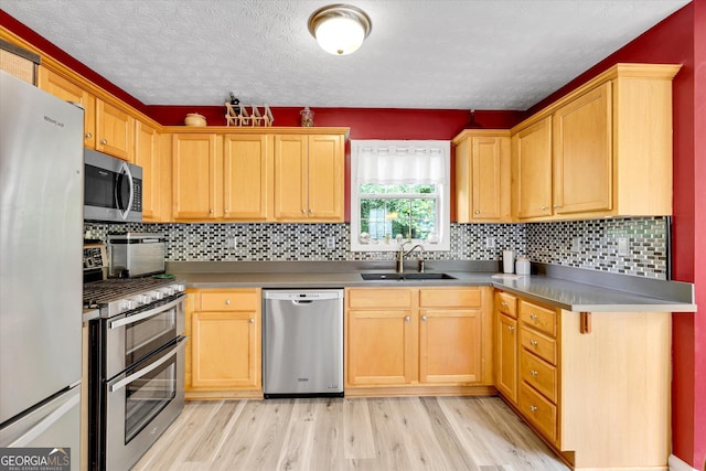 52 Cherub Ln, Sharpsburg, GA 30277 - kitchen featuring appliances with stainless steel finishes, light wood-style flooring, a textured ceiling, backsplash, and light brown cabinetry