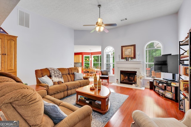 52 Cherub Ln, Sharpsburg, GA 30277 - living area featuring a ceiling fan, a textured ceiling, wood-type flooring, a fireplace, and a towering ceiling