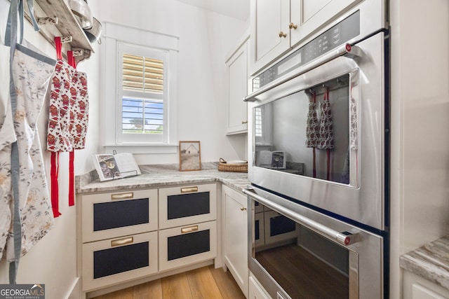 639 Frank Crook Rd, Canon, GA 30520 - kitchen with double oven, light wood-style floors, white cabinetry, and light stone counters