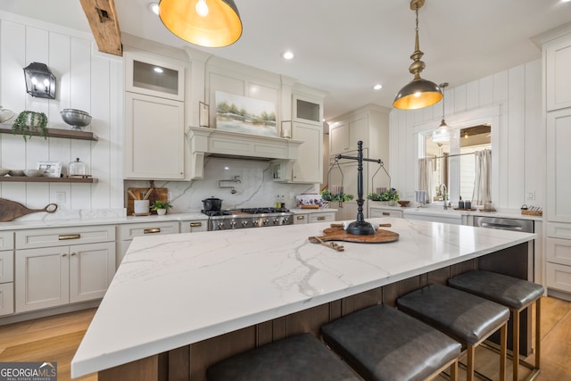 639 Frank Crook Rd, Canon, GA 30520 - kitchen with a breakfast bar, tasteful backsplash, light wood-type flooring, a center island, and glass insert cabinets