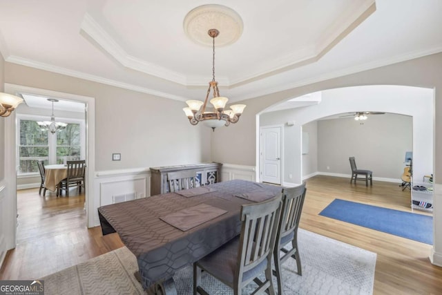 3887 Hickory Manor Dr, Suwanee, GA 30024 - dining space featuring a chandelier, a raised ceiling, arched walkways, wood finished floors, and ornamental molding