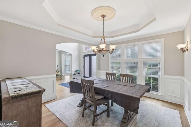 3887 Hickory Manor Dr, Suwanee, GA 30024 - dining area with arched walkways, a chandelier, a wainscoted wall, a raised ceiling, and light wood finished floors