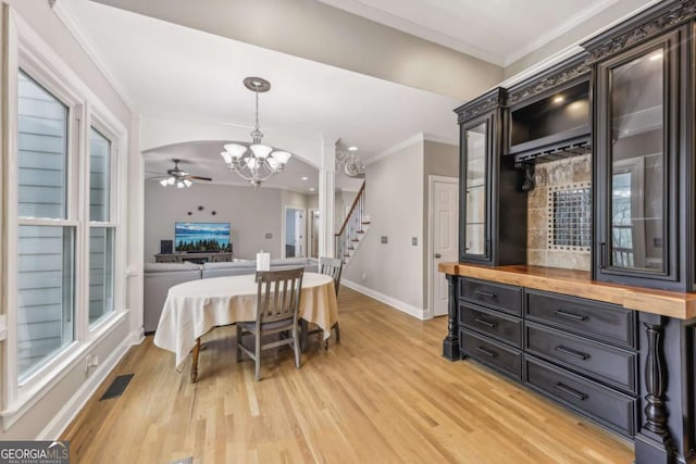 3887 Hickory Manor Dr, Suwanee, GA 30024 - dining area featuring a chandelier, a ceiling fan, ornamental molding, light wood-style floors, and stairs