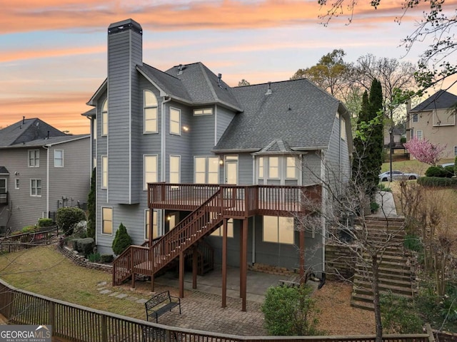 3887 Hickory Manor Dr, Suwanee, GA 30024 - back of house at dusk featuring stairway, a deck, a patio, a fenced backyard, and a chimney