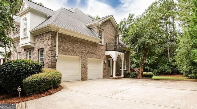 35 Inverleigh Row, Covington, GA 30014 - view of side of property with driveway, brick siding, roof with shingles, a balcony, and an attached garage