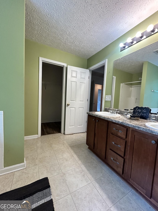 375 Sapphire Bnd, Riverdale, GA 30296 - full bathroom with double vanity, a textured ceiling, tile patterned flooring, a shower, and a walk in closet