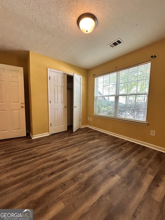 375 Sapphire Bnd, Riverdale, GA 30296 - unfurnished bedroom featuring dark wood finished floors, a textured ceiling, and a closet