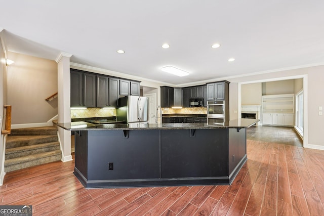 4685 Braselton Hwy, Hoschton, GA 30548 - kitchen with appliances with stainless steel finishes, a breakfast bar, crown molding, backsplash, and dark stone counters