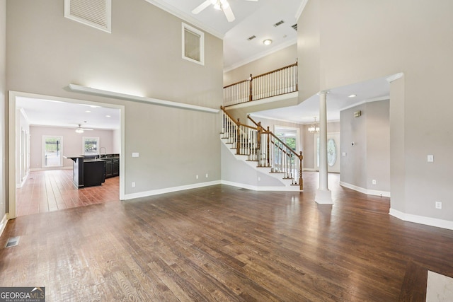 4685 Braselton Hwy, Hoschton, GA 30548 - unfurnished living room featuring ceiling fan, a high ceiling, crown molding, wood finished floors, and decorative columns