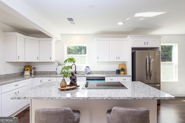 932 Brian Ln, Forest Park, GA 30297 - kitchen with freestanding refrigerator, a kitchen bar, black electric cooktop, white cabinetry, and dark wood finished floors