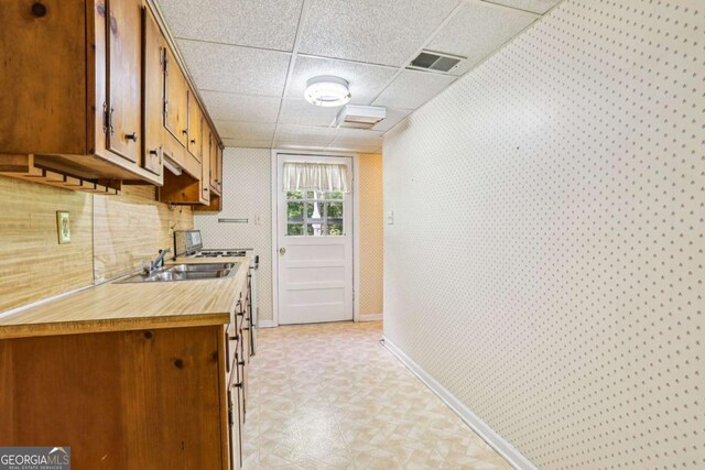 415 Haven Ln, Marietta, GA 30066 - kitchen with light countertops, wallpapered walls, brown cabinetry, a paneled ceiling, and light floors