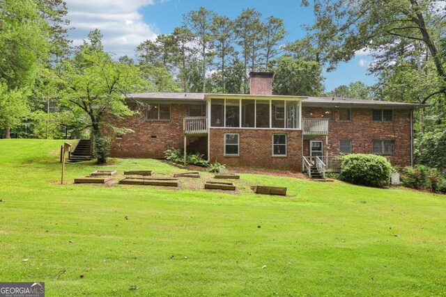 415 Haven Ln, Marietta, GA 30066 - back of house with a chimney, a sunroom, brick siding, and a lawn