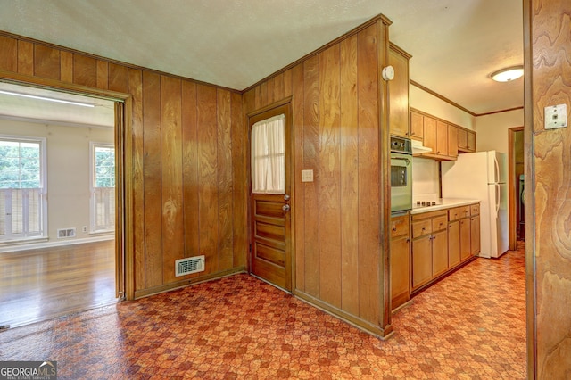 5739 Cobb Mdw, Norcross, GA 30093 - kitchen with freestanding refrigerator, stainless steel oven, ornamental molding, wooden walls, and brown cabinetry