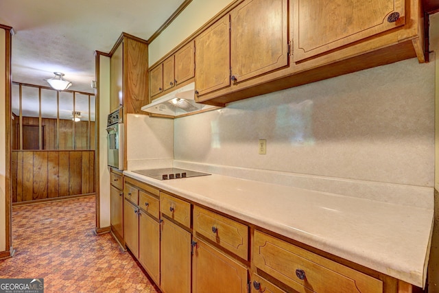 5739 Cobb Mdw, Norcross, GA 30093 - kitchen featuring under cabinet range hood, black electric stovetop, brown cabinets, light countertops, and wood walls