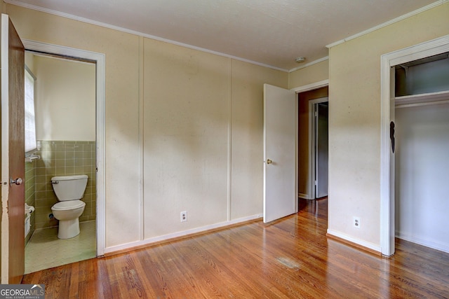 5739 Cobb Mdw, Norcross, GA 30093 - unfurnished bedroom featuring wood finished floors, crown molding, connected bathroom, a closet, and tile walls