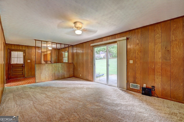 5739 Cobb Mdw, Norcross, GA 30093 - unfurnished living room with healthy amount of natural light, carpet floors, wooden walls, a ceiling fan, and a textured ceiling