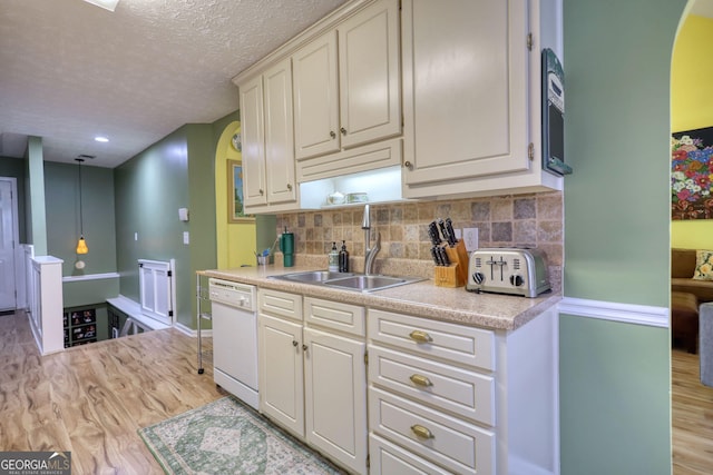 1248 Rockview Ct, Loganville, GA 30052 - kitchen featuring white dishwasher, light countertops, light wood finished floors, arched walkways, and a textured ceiling
