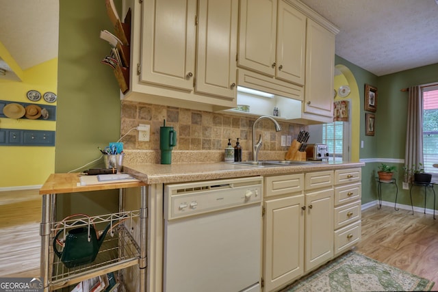1248 Rockview Ct, Loganville, GA 30052 - kitchen featuring dishwasher, light countertops, light wood-type flooring, cream cabinetry, and decorative backsplash