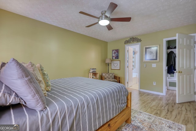 1248 Rockview Ct, Loganville, GA 30052 - bedroom with a textured ceiling, wood finished floors, ensuite bath, and ceiling fan