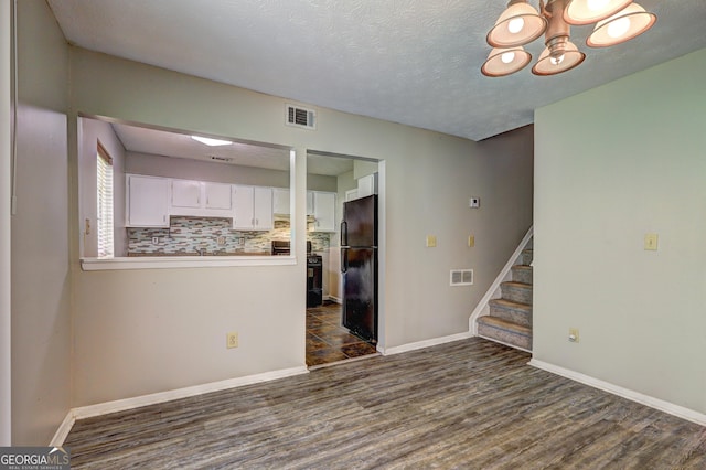 5026 Brittany Dr, Stone Mountain, GA 30083 - unfurnished room featuring dark wood-style floors, stairway, a chandelier, and a textured ceiling