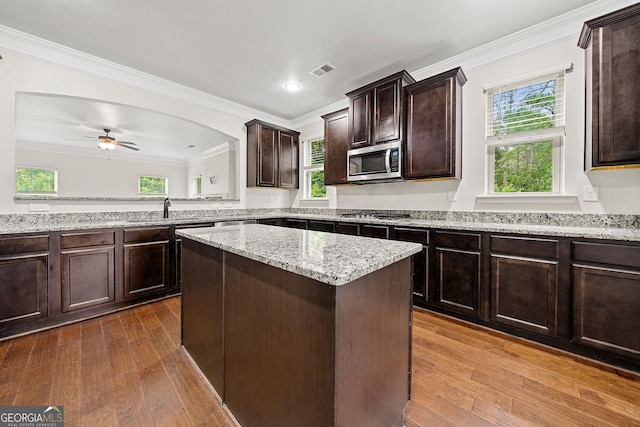 3865 Rifflepool Ct, Douglasville, GA 30135 - kitchen featuring appliances with stainless steel finishes, dark brown cabinets, crown molding, dark wood-type flooring, and light stone countertops