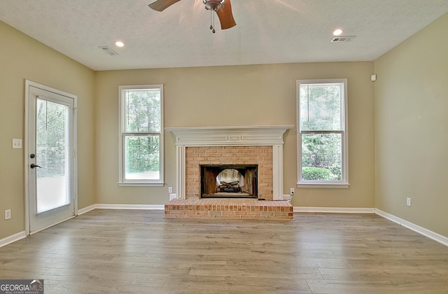 1709 Reese Rd, Sharpsburg, GA 30277 - unfurnished living room with wood-type flooring, a textured ceiling, ceiling fan, healthy amount of natural light, and a brick fireplace