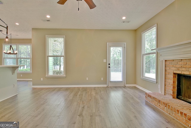 1709 Reese Rd, Sharpsburg, GA 30277 - unfurnished living room featuring light wood-style flooring, a brick fireplace, ceiling fan, a textured ceiling, and recessed lighting
