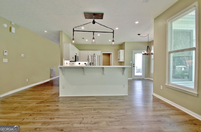 1709 Reese Rd, Sharpsburg, GA 30277 - kitchen featuring stainless steel fridge with ice dispenser, a kitchen bar, white cabinetry, light wood-style flooring, and a chandelier