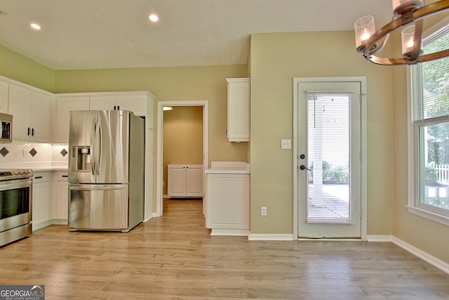 1709 Reese Rd, Sharpsburg, GA 30277 - kitchen featuring appliances with stainless steel finishes, a chandelier, white cabinetry, light wood finished floors, and light countertops