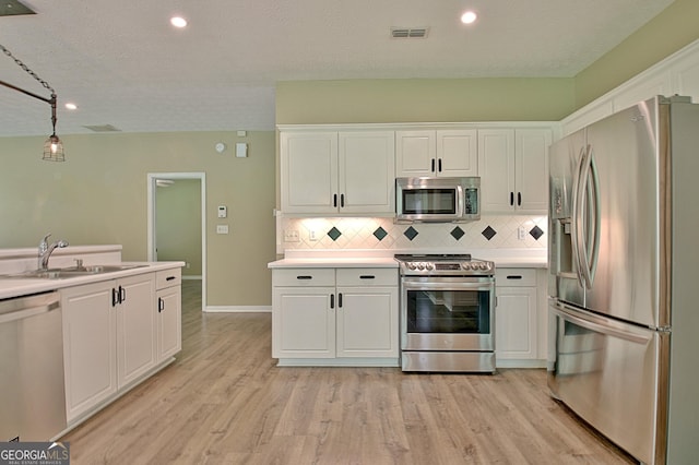 1709 Reese Rd, Sharpsburg, GA 30277 - kitchen featuring appliances with stainless steel finishes, white cabinetry, light wood-style flooring, tasteful backsplash, and recessed lighting