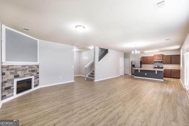 243 Flowing Meadows Dr, Kathleen, GA 31047 - unfurnished living room with stairway, light wood-style floors, a chandelier, and a fireplace