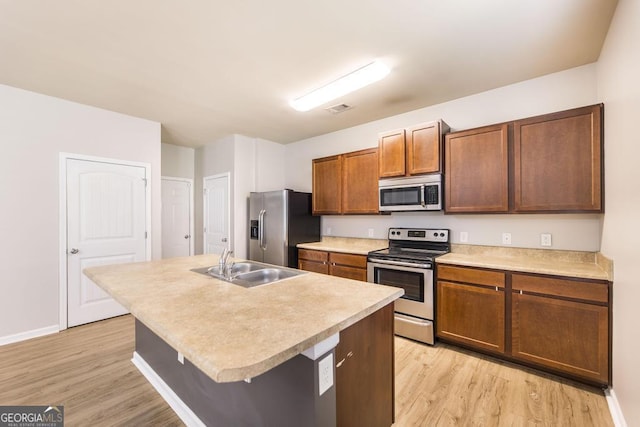 243 Flowing Meadows Dr, Kathleen, GA 31047 - kitchen featuring stainless steel appliances, light wood finished floors, light countertops, and an island with sink