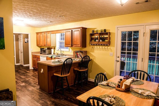 1665 Jackson Lake Rd, Mansfield, GA 30055 - kitchen featuring a textured ceiling, a kitchen breakfast bar, dark wood-style floors, brown cabinetry, and a peninsula