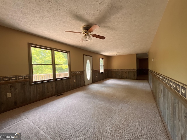 172 Fred Henry Ln, Clayton, GA 30525 - spare room featuring wainscoting, a textured ceiling, wooden walls, ceiling fan, and carpet flooring