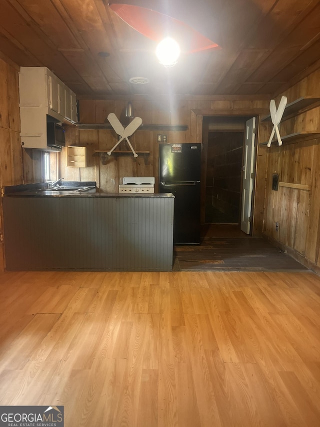 172 Fred Henry Ln, Clayton, GA 30525 - kitchen featuring freestanding refrigerator, wood finished floors, dark countertops, wooden walls, and a peninsula
