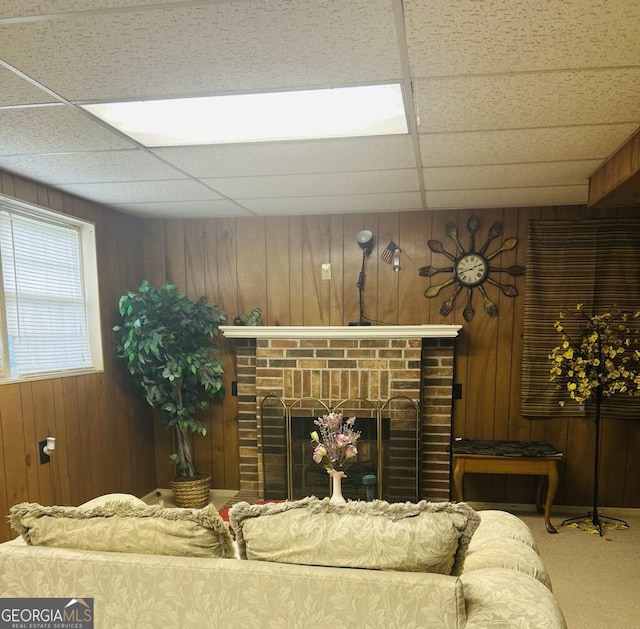 2235 Lyn Ct, Macon, GA 31206 - living room featuring wood walls, a brick fireplace, carpet floors, and a drop ceiling