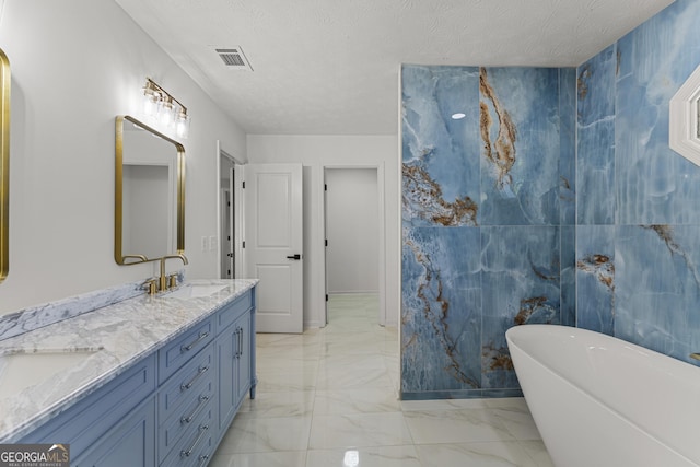 5437 Chatham Woods Ct, Columbus, GA 31907 - bathroom with marble look tiles, a soaking tub, double vanity, and a textured ceiling