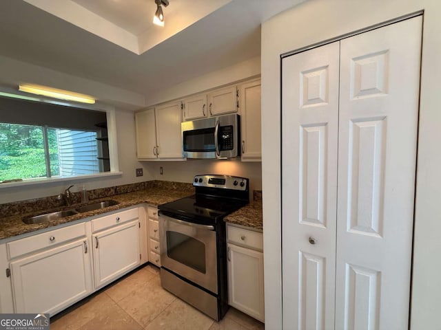 40 Dunwoody Springs Dr, Atlanta, GA 30328 - kitchen with stainless steel appliances, light tile patterned flooring, dark stone counters, and white cabinets