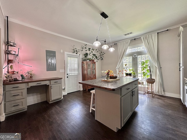 6192 Collins St NE, Covington, GA 30014 - kitchen featuring dark wood-style flooring, a breakfast bar area, a center island, pendant lighting, and crown molding