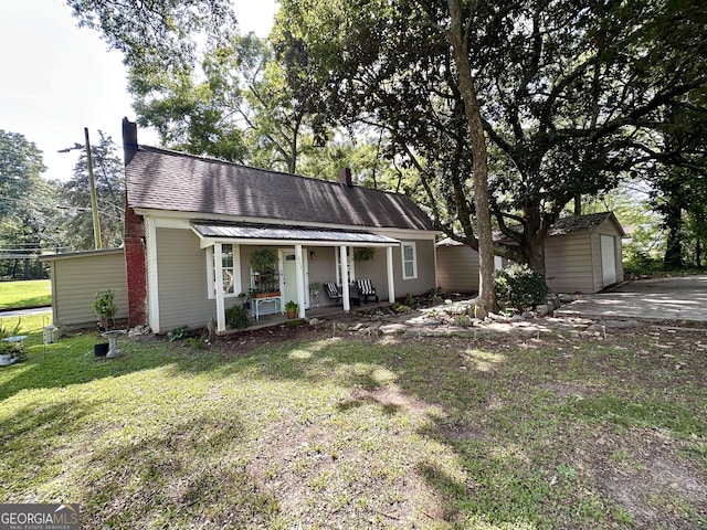 6192 Collins St NE, Covington, GA 30014 - view of front of house with a porch, an outdoor structure, a front lawn, and a chimney