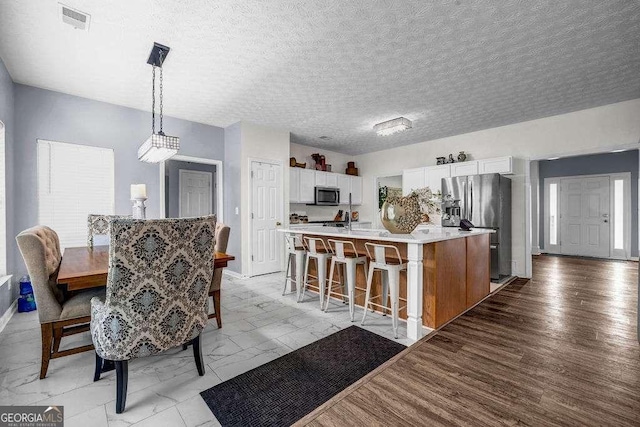 15 Saddlebrook Ct, Covington, GA 30016 - kitchen featuring stainless steel appliances, light countertops, white cabinetry, a textured ceiling, and a breakfast bar area