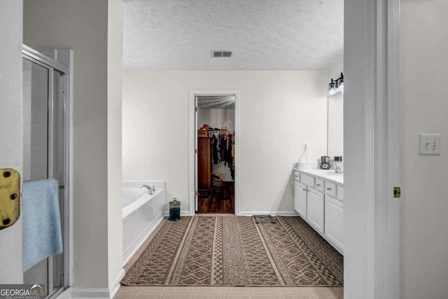 15 Saddlebrook Ct, Covington, GA 30016 - bathroom featuring vanity, a bath, a spacious closet, a shower stall, and a textured ceiling