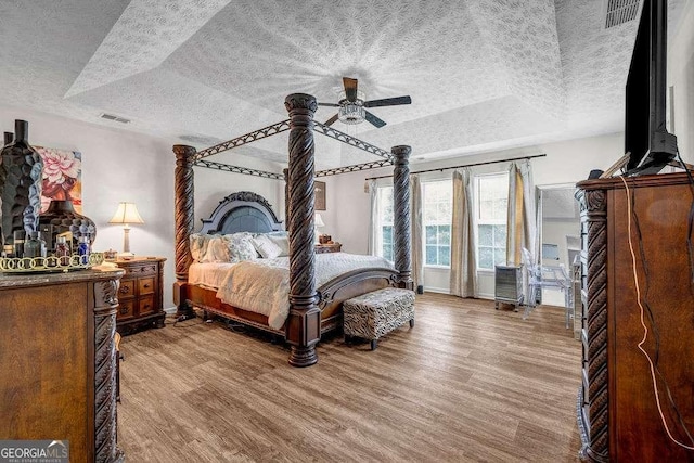 15 Saddlebrook Ct, Covington, GA 30016 - bedroom with a textured ceiling, wood finished floors, a tray ceiling, and a ceiling fan