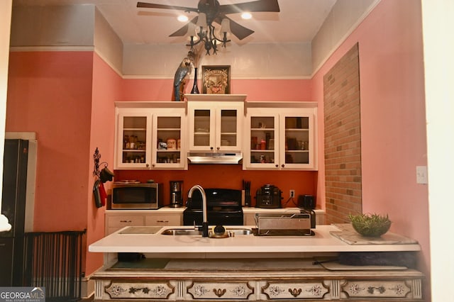 5321 Oak St, Eastman, GA 31023 - kitchen with stainless steel microwave, ceiling fan, under cabinet range hood, light countertops, and glass insert cabinets