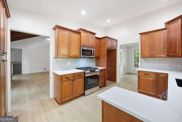 3292 Holly Mill Ct, Marietta, GA 30062 - kitchen featuring stainless steel appliances, brown cabinets, light countertops, a wainscoted wall, and tasteful backsplash