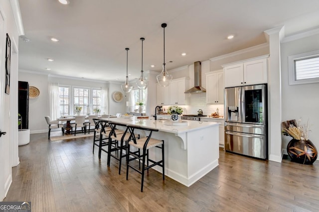 767 Farmstead Rd, Suwanee, GA 30024 - kitchen featuring stainless steel fridge, wall chimney range hood, crown molding, a kitchen breakfast bar, and an island with sink