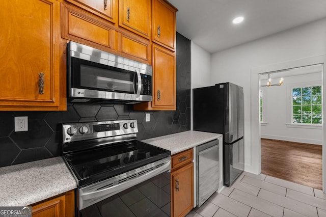 3105 Woodlawn Ave, Columbus, GA 31904 - kitchen with stainless steel appliances, brown cabinetry, tasteful backsplash, a chandelier, and recessed lighting