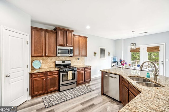 2755 Evan Manor Ln, Cumming, GA 30041 - kitchen featuring appliances with stainless steel finishes, light wood-type flooring, tasteful backsplash, light stone countertops, and pendant lighting