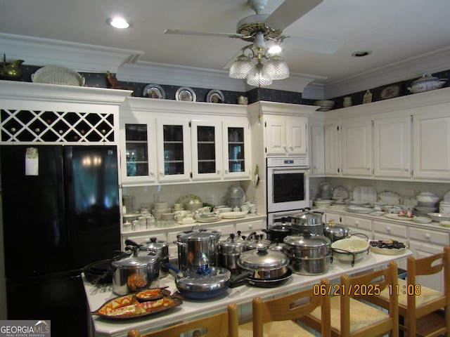 5523 Bahia Mar Cir, Stone Mountain, GA 30087 - kitchen featuring freestanding refrigerator, crown molding, a ceiling fan, white cabinetry, and white double oven