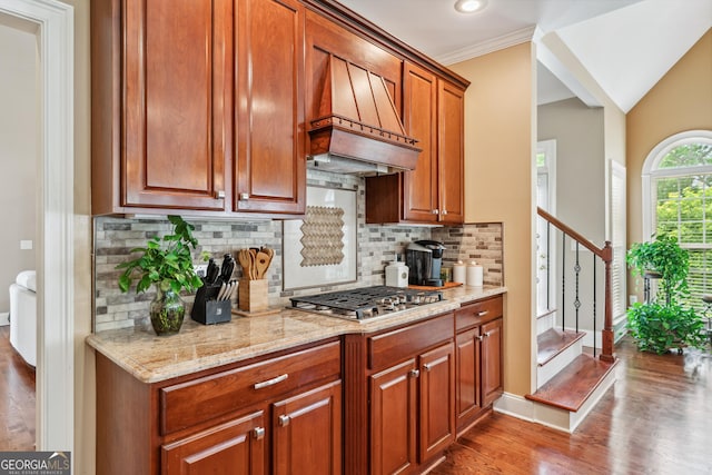 106 April Walk, Mcdonough, GA 30253 - kitchen with custom exhaust hood, wood finished floors, stainless steel gas stovetop, light stone counters, and backsplash